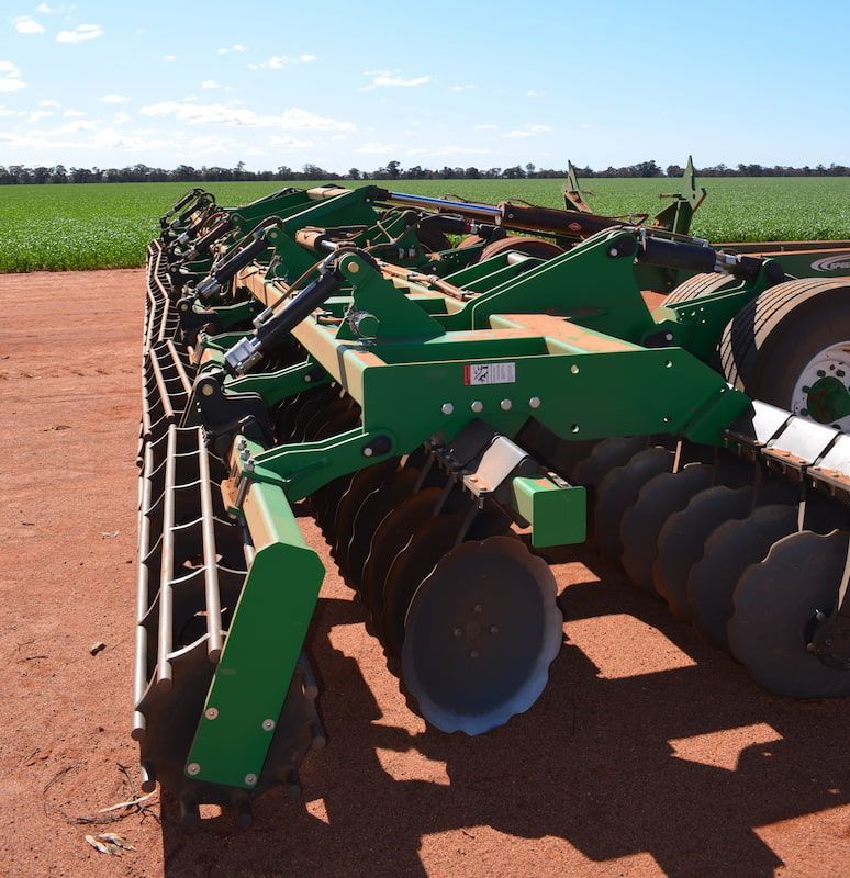 A Green Tractor Is Parked in A Dirt Field — Cheshire Machinery in Bundaberg, QLD
