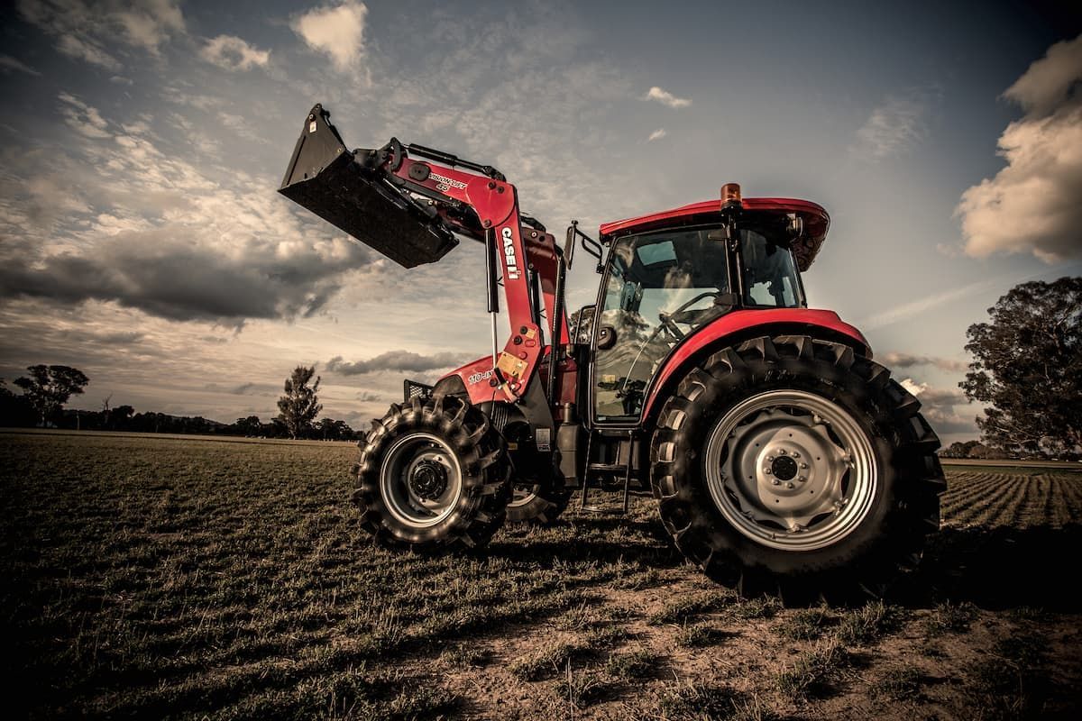 A Red Tractor with A Front Loader Is Parked in A Field — Cheshire Machinery in Murgon, QLD