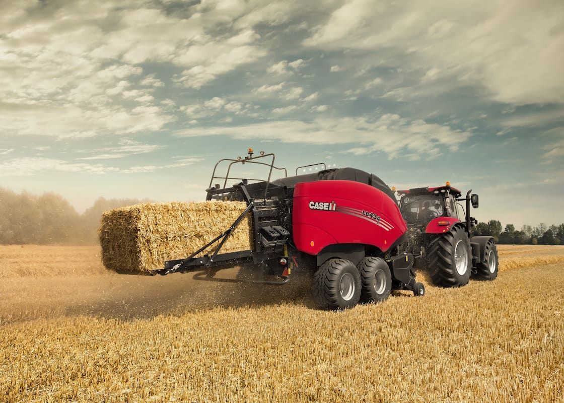 A Tractor Is Baling Hay in A Field — Cheshire Machinery in Murgon, QLD