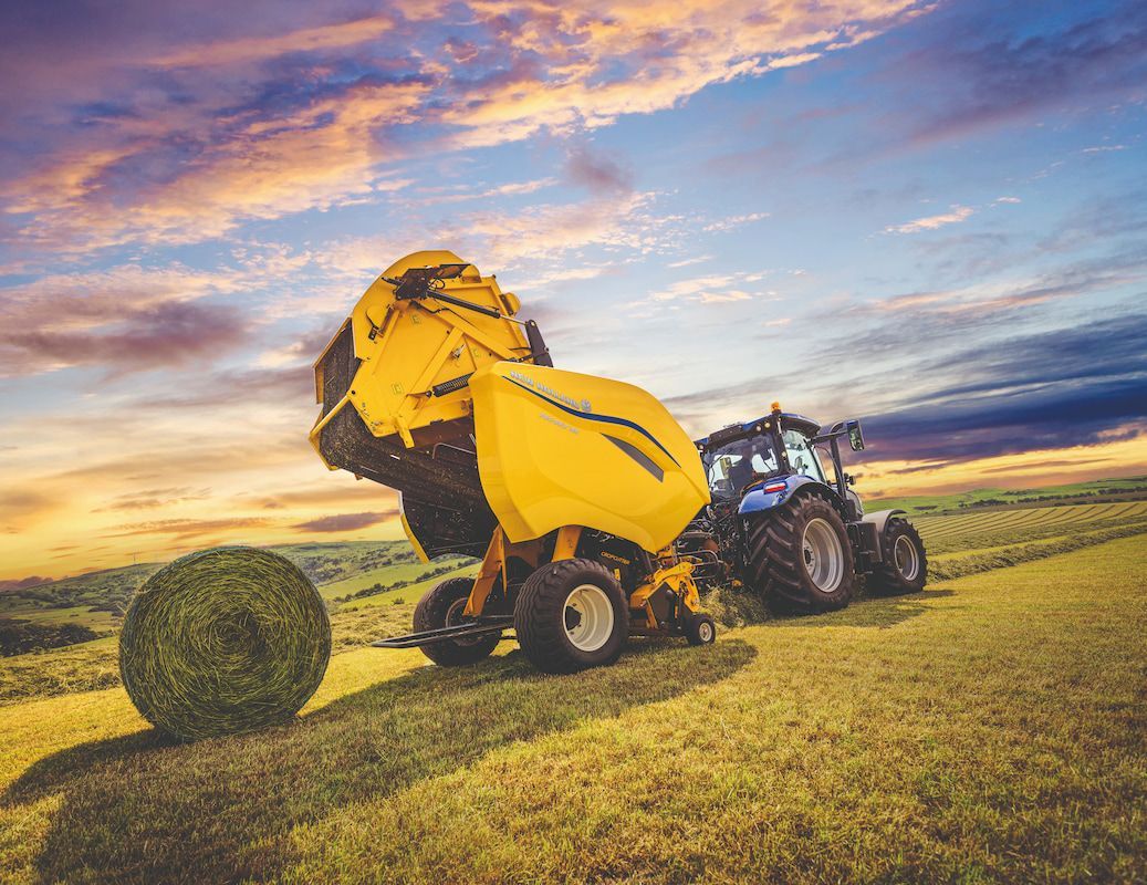 A Tractor Is Baling Hay in A Field at Sunset — Cheshire Machinery in Svensson Heights, QLD