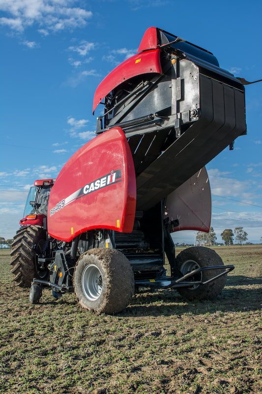 A Red Tractor Is Sitting in A Field with Its Hood Open — Cheshire Machinery in Svensson Heights, QLD