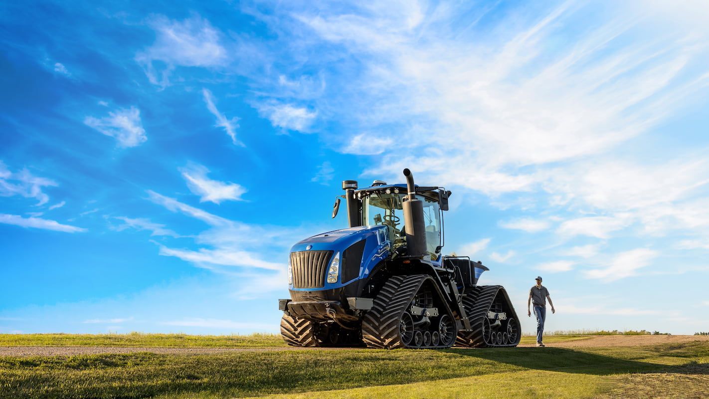 A Man Is Walking Towards a Tractor in A Field — Cheshire Machinery in Bundaberg, QLD
