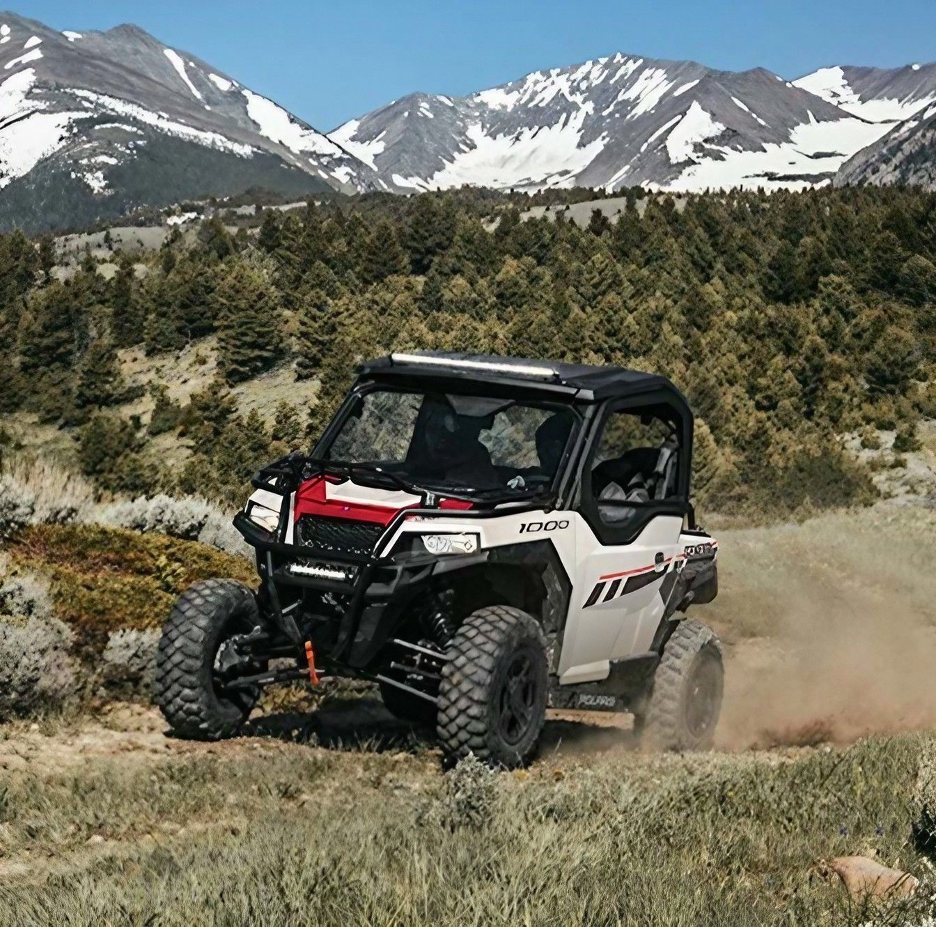 A White ATV Is Driving Down a Dirt Road with Mountains in The Background — Cheshire Machinery in Svensson Heights, QLD