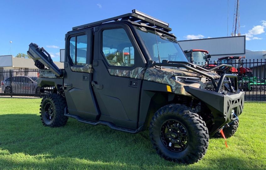 A Black Utility Vehicle Is Parked in A Grassy Field — Cheshire Machinery in Bundaberg, QLD