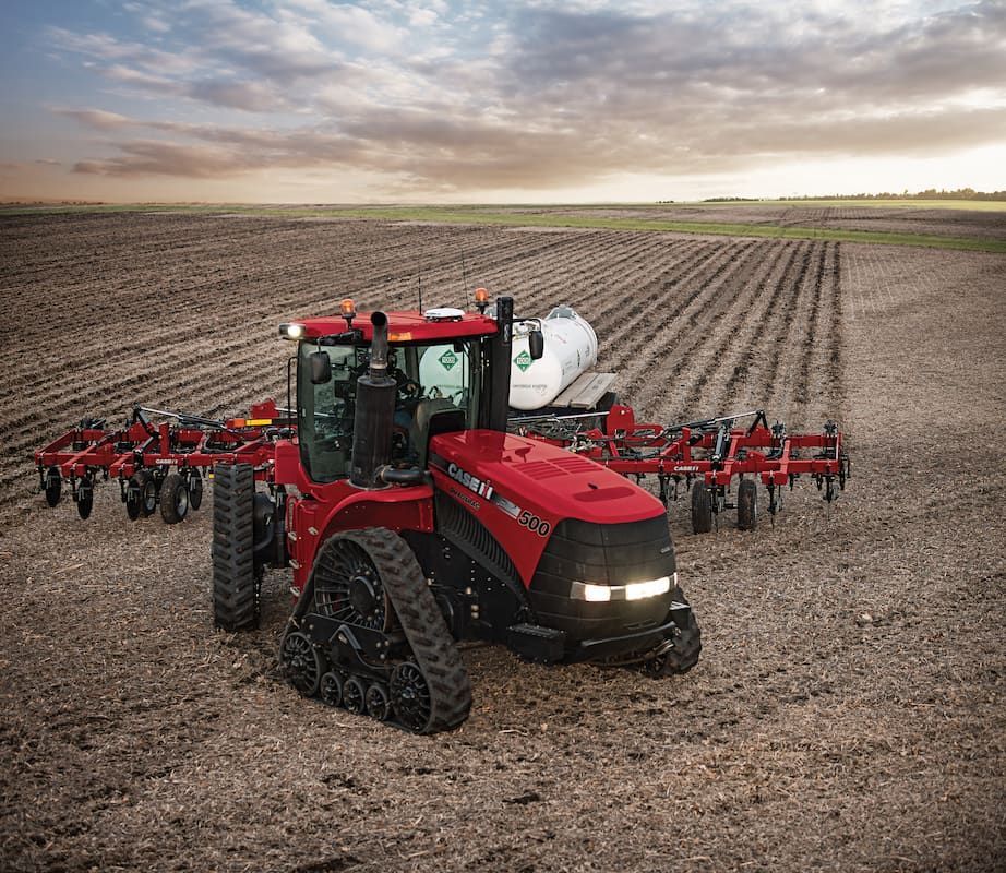 A Red Tractor Is Plowing a Field with A Plow Attached to It — Cheshire Machinery in Svensson Heights, QLD