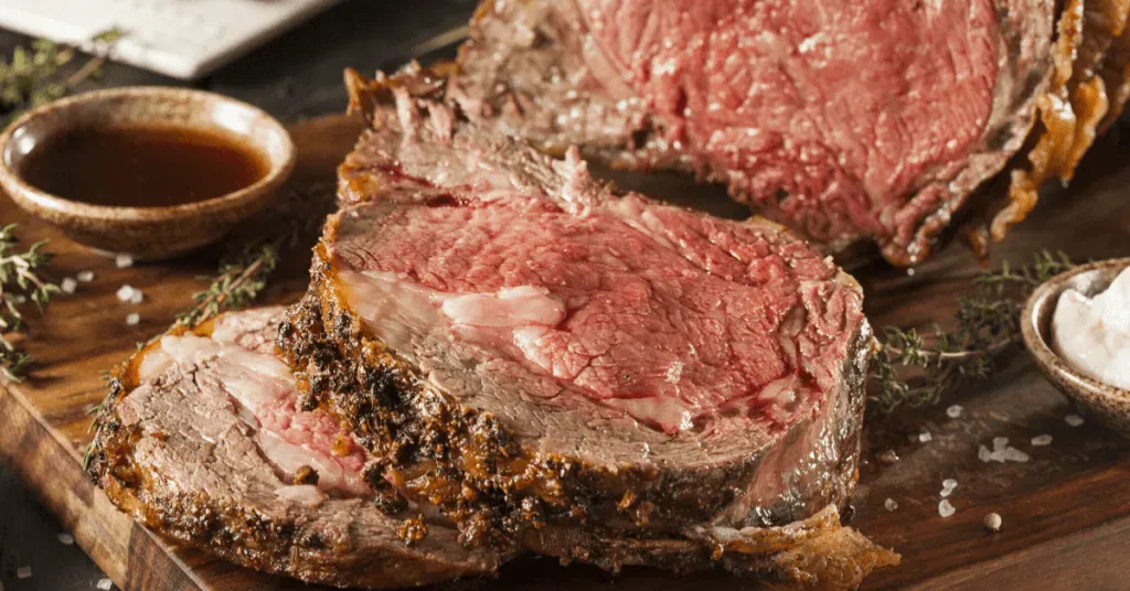 A slice of roast beef is sitting on top of a wooden cutting board.