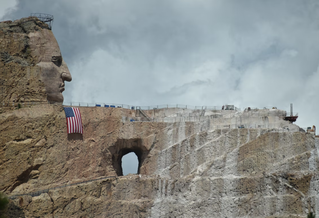 A statue of a man 's head is sitting on top of a rocky hill.