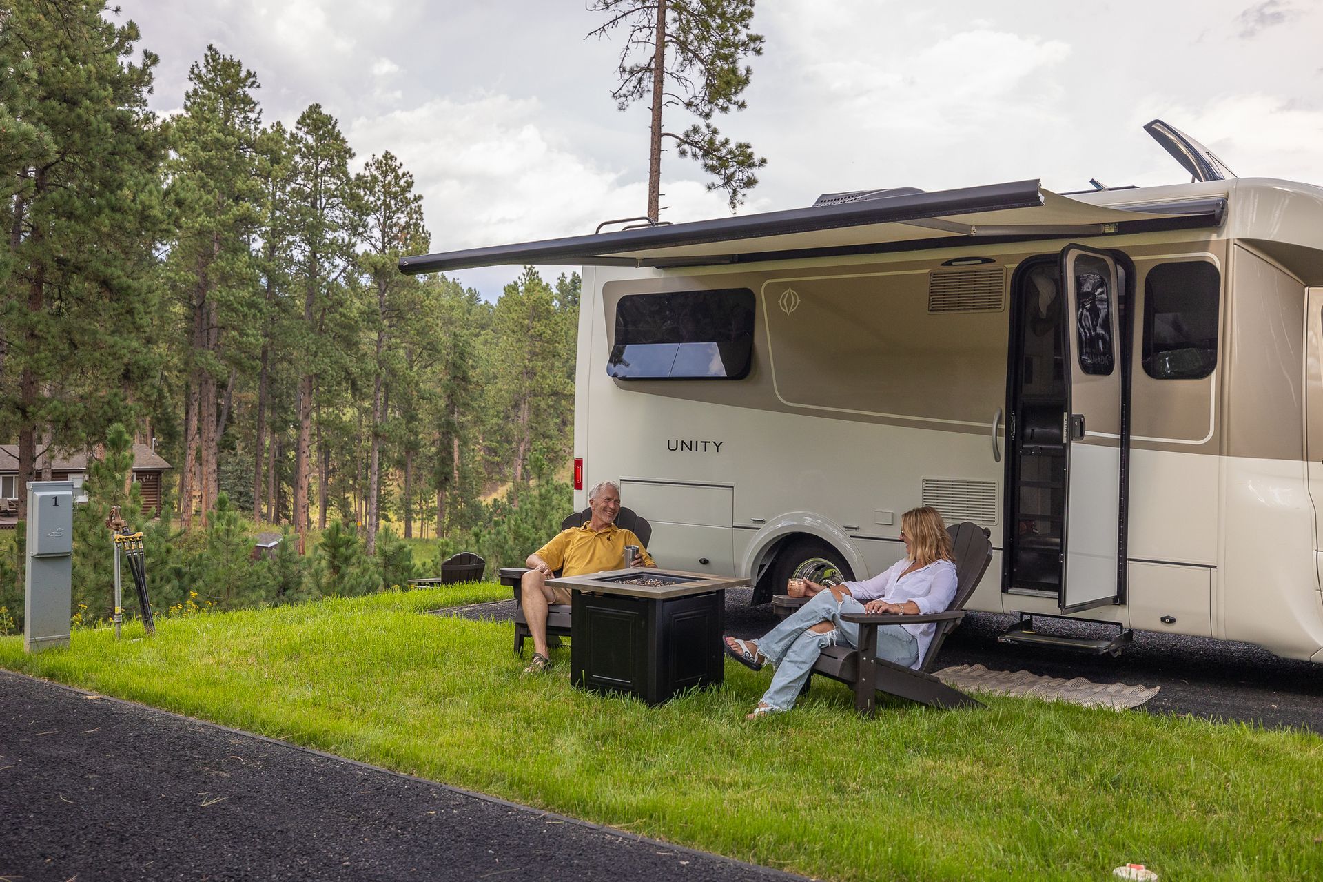 A man and a woman are sitting in chairs in front of a rv.