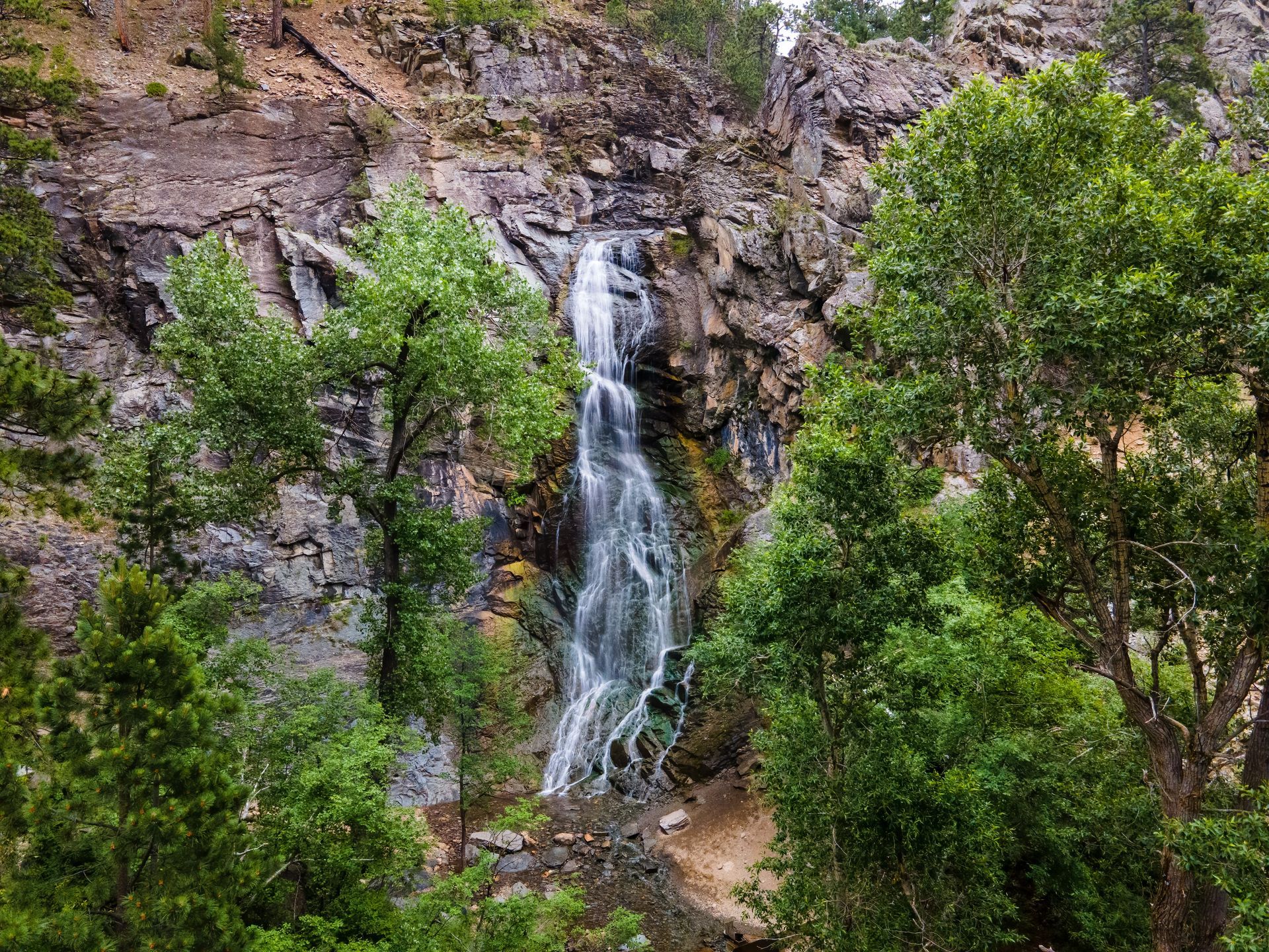 A waterfall is surrounded by trees on a rocky cliff.