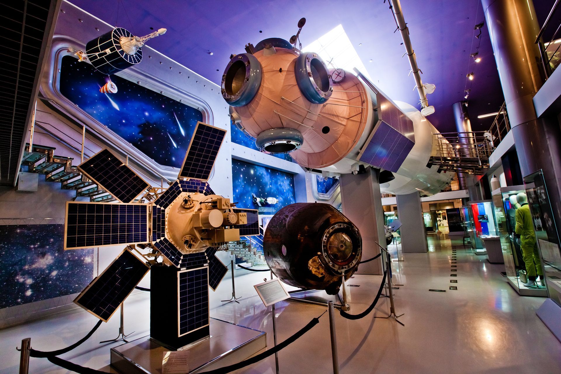 A satellite and a space shuttle are on display in a museum