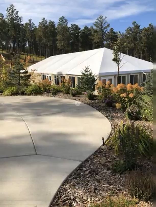 A large white tent is sitting in the middle of a forest.