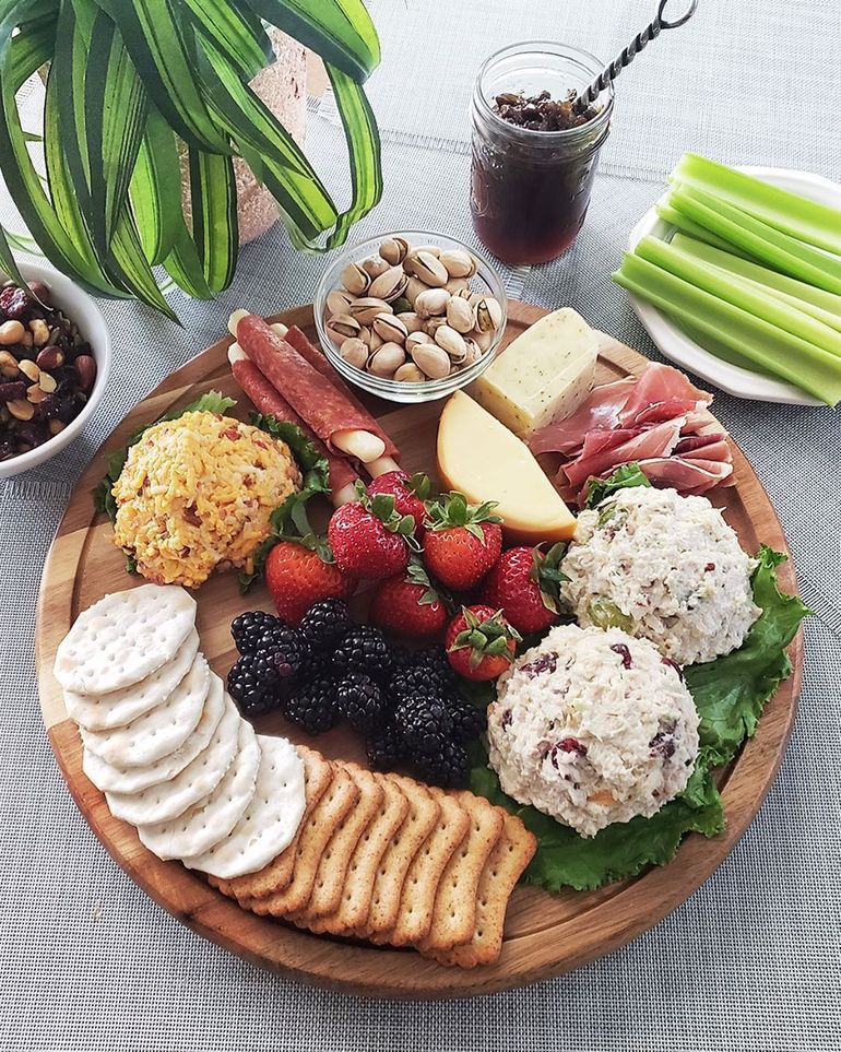 A white plate topped with a sausage , eggs , fruit and a salad.