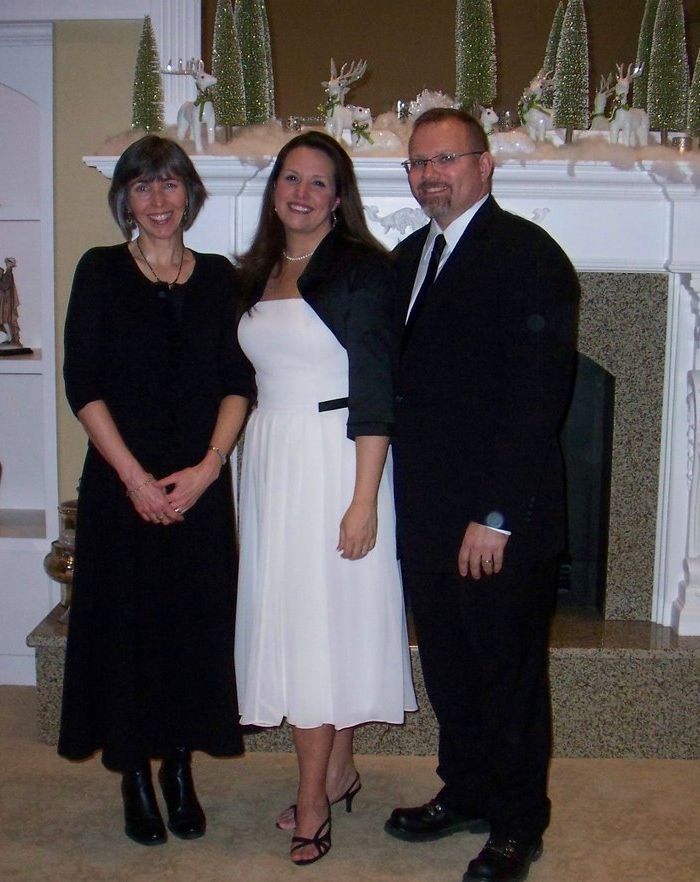 A man and two women pose for a picture in front of a fireplace