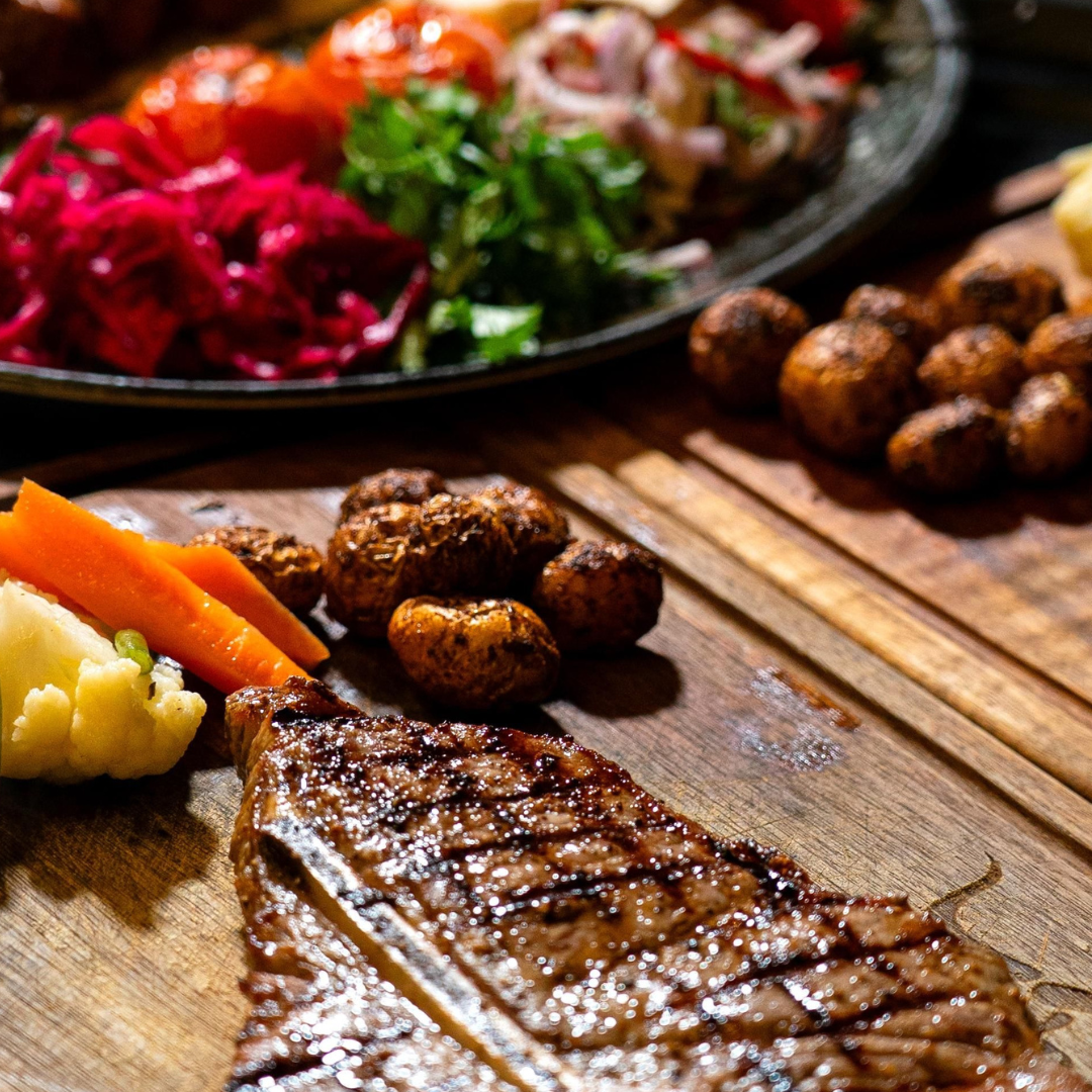 a steak dinner and veggies on a cutting board