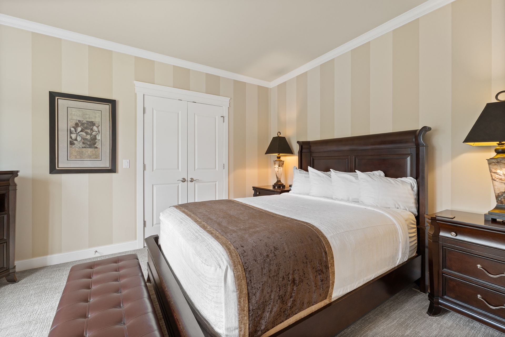A hotel room with a king size bed , chair , dresser and window.