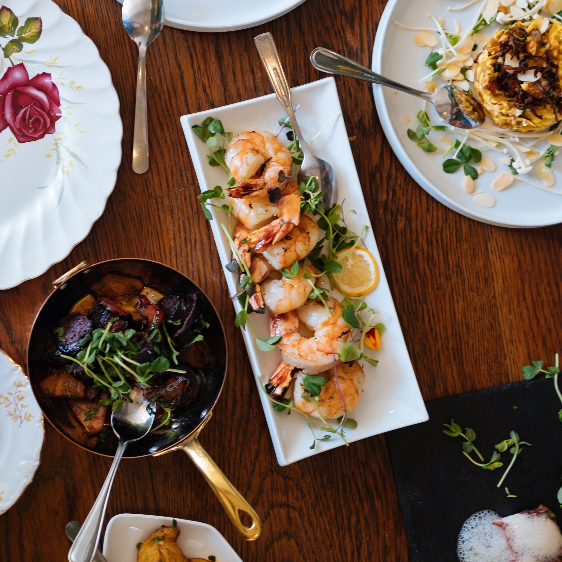 A wooden table topped with plates of food including shrimp