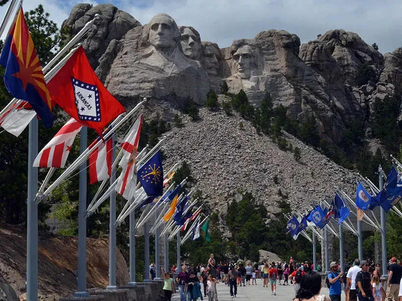 A row of flags are lined up in front of a mountain