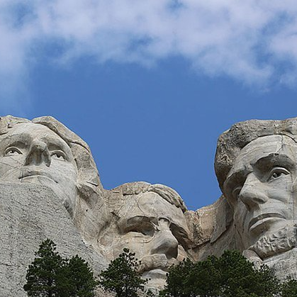 A statue of a man 's face is carved into the side of a mountain.