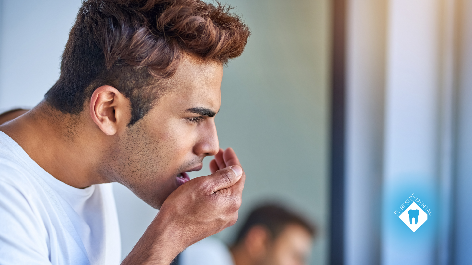 A man is coughing in front of a mirror.