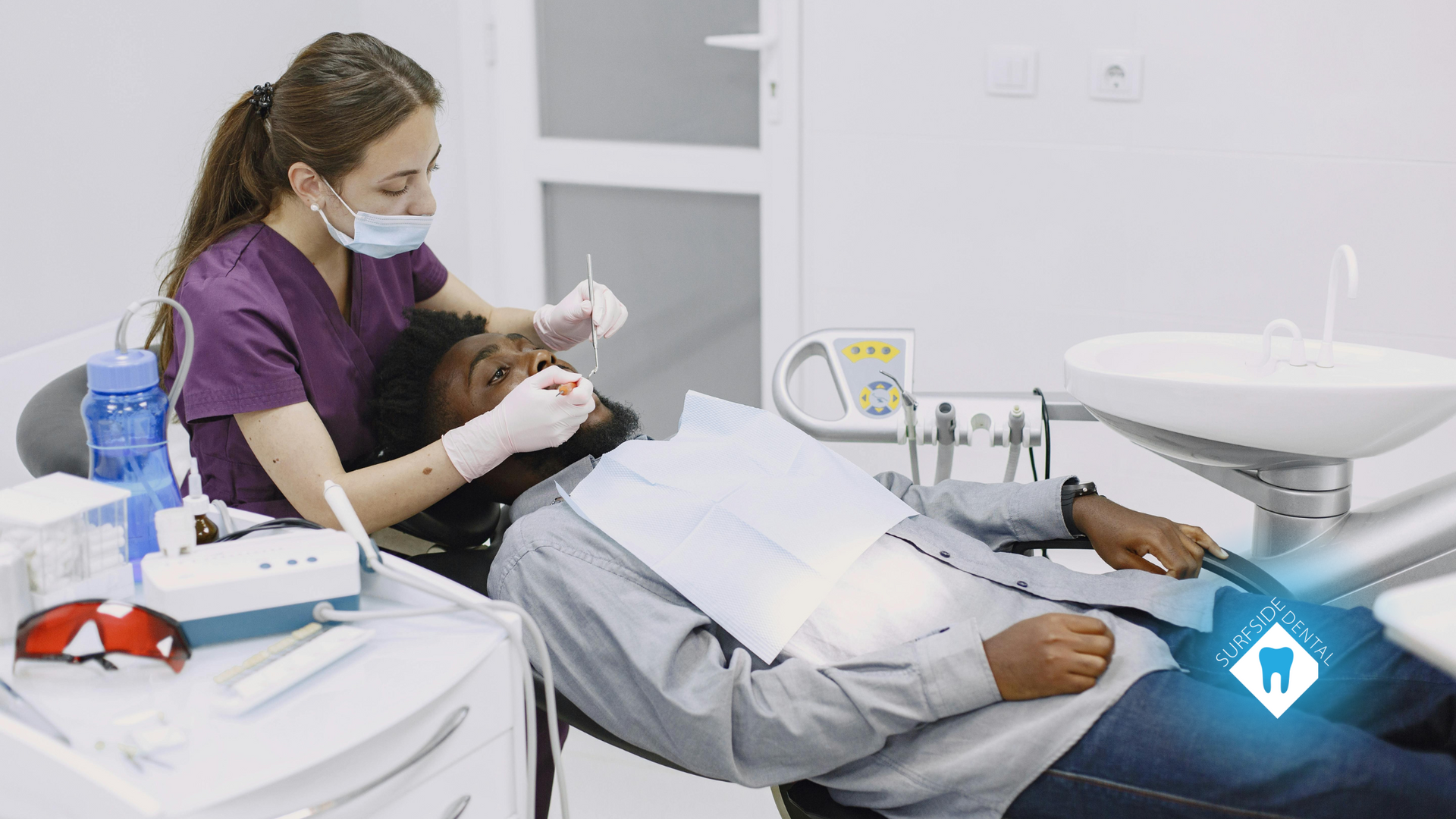 A man is laying in a dental chair while a dentist examines his teeth.