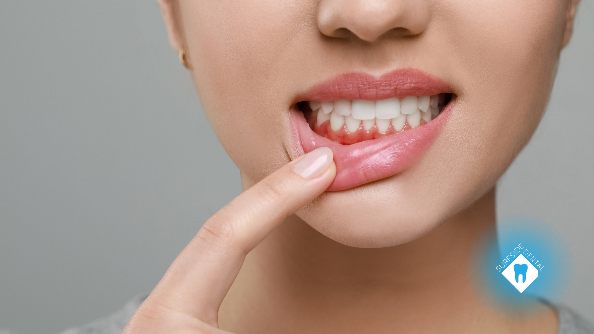 A woman is pointing at her teeth with her finger.