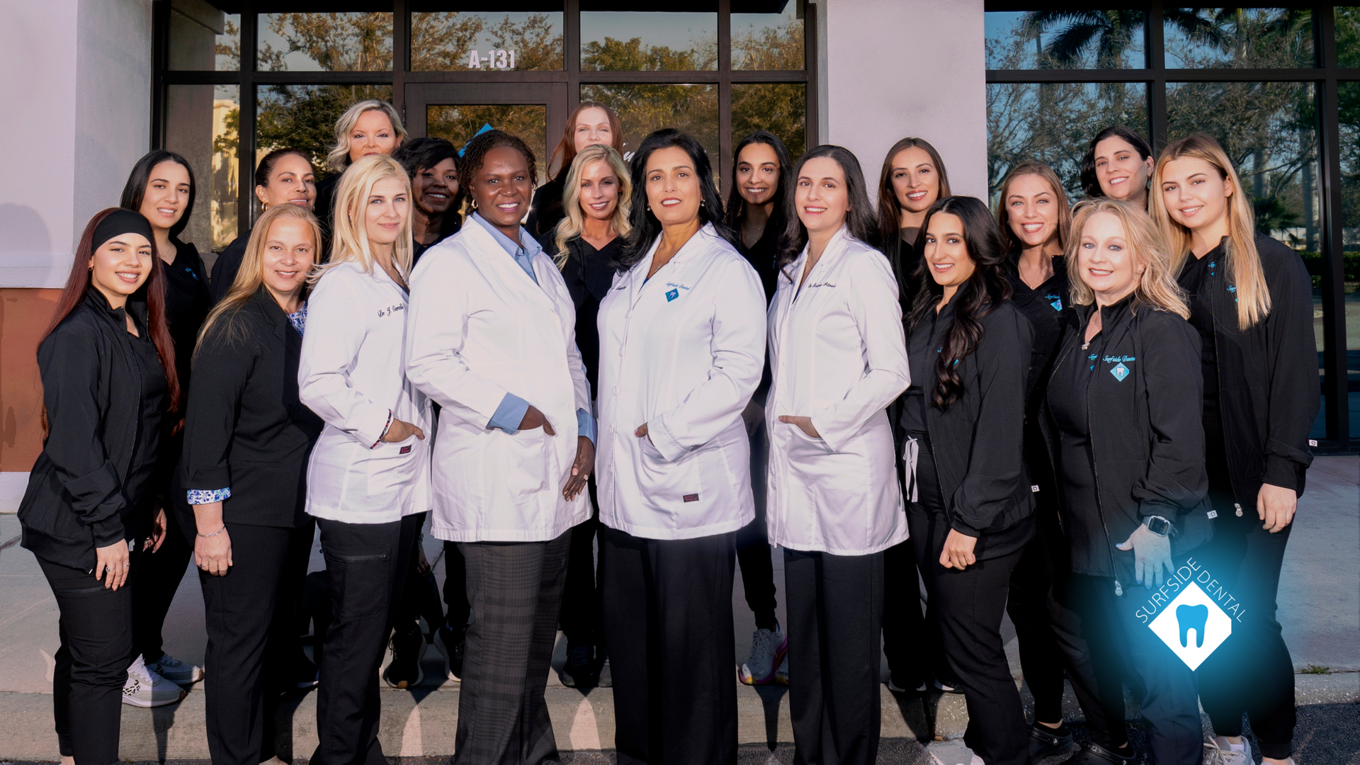 A group of doctors and nurses are posing for a picture in front of a building.