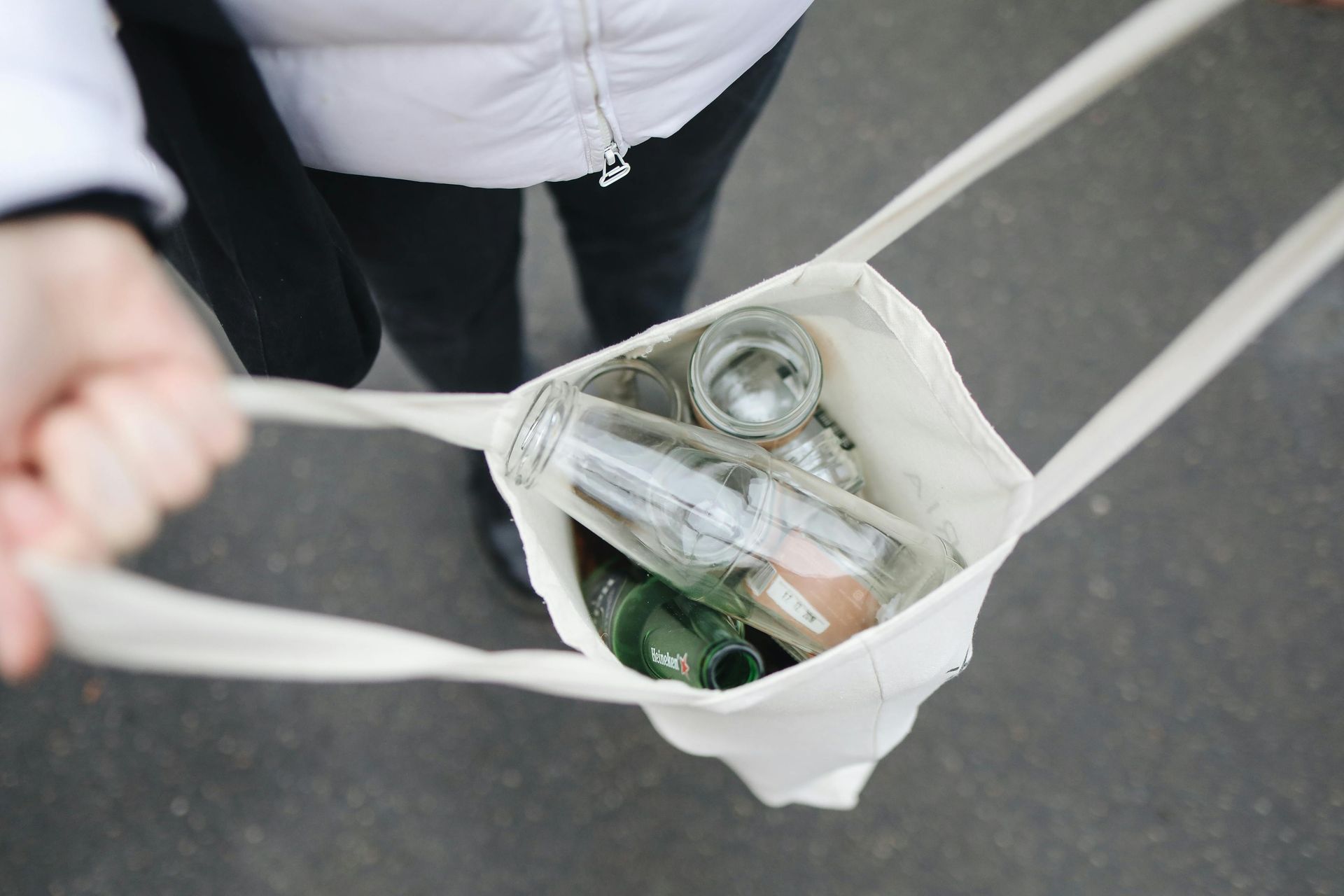 Una persona sostiene una bolsa llena de botellas y latas.