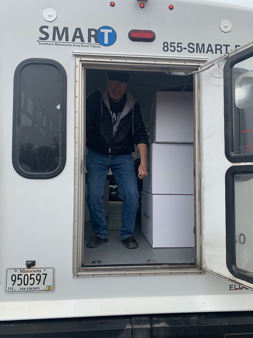 Person standing in the open doorway of a white SMART van with cabinets inside