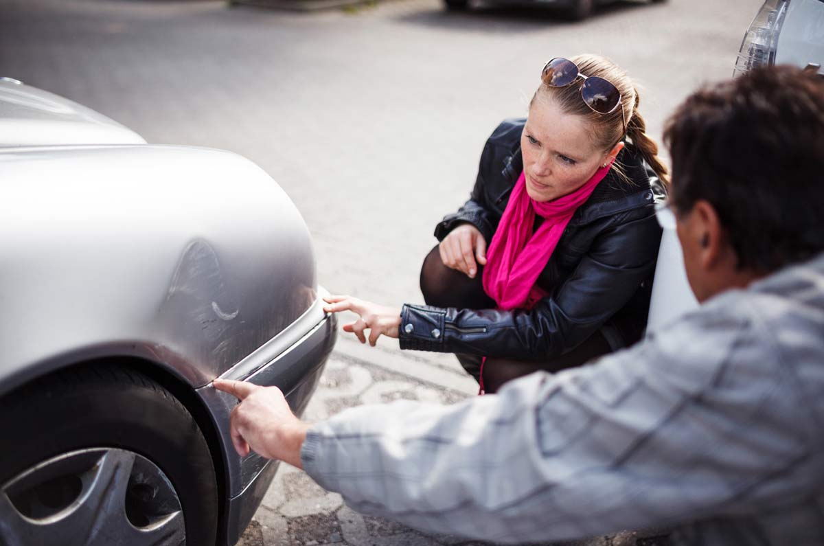 Two people are looking at a damaged car — Fall River, MA — Collision Repair Shop