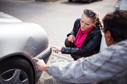 Two people are looking at a damaged car — Fall River, MA — Collision Repair Shop