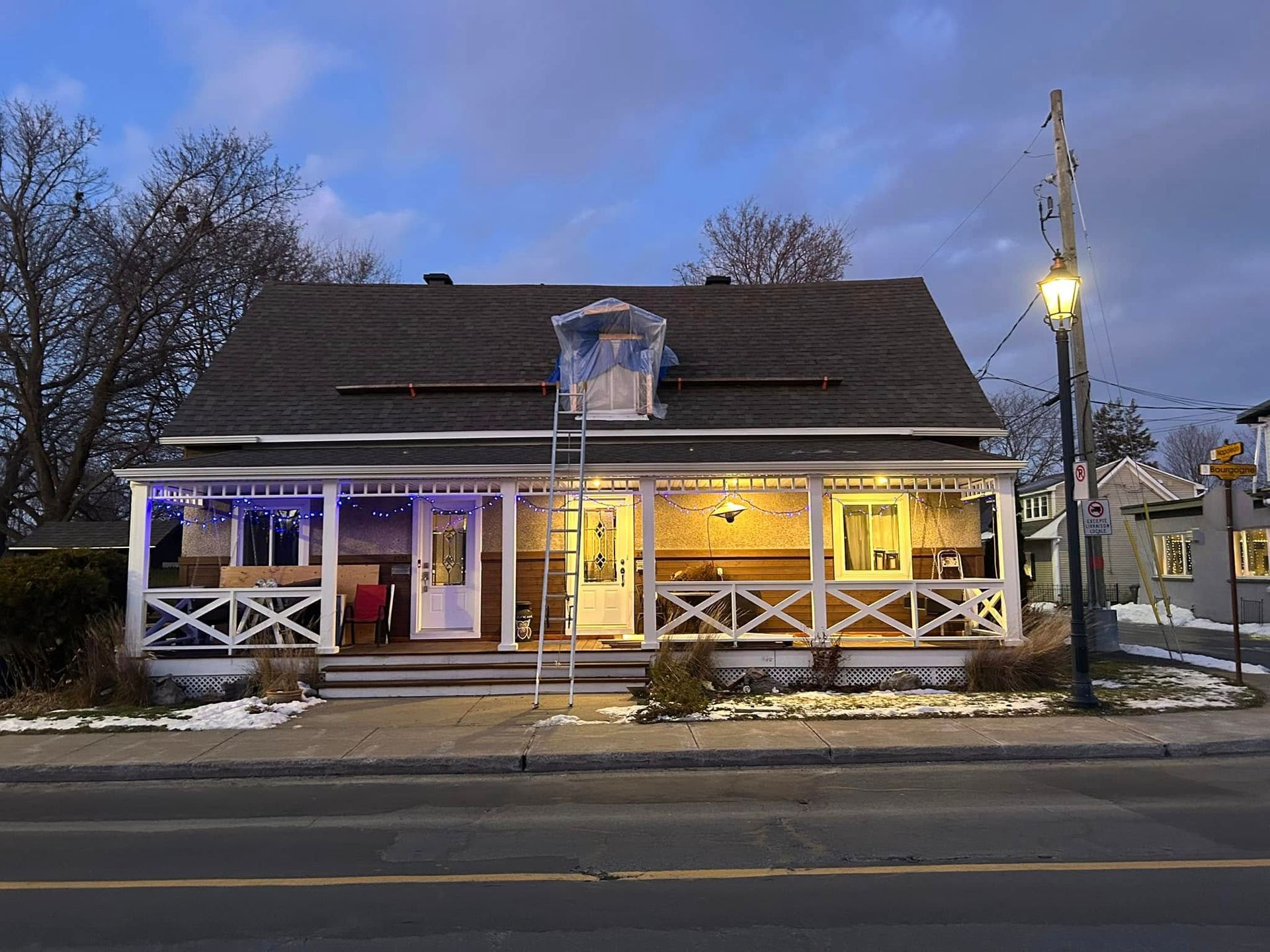 Une maison avec un porche et des lumières de Noël se trouve sur le côté de la route.