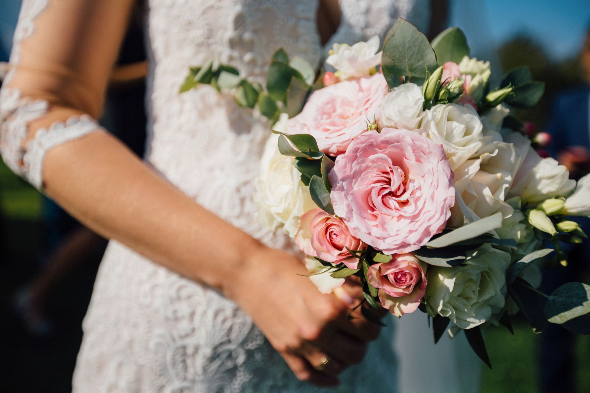 A bride in a white dress is holding a bouquet of pink and white flowers.