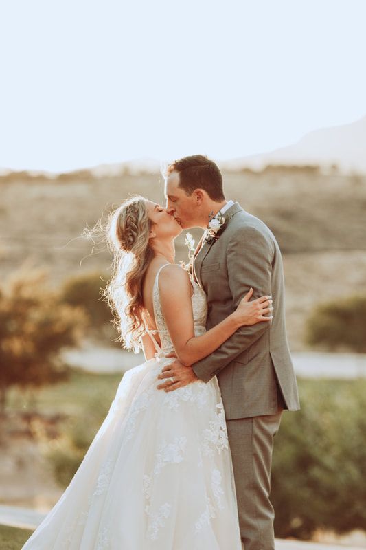 A bride and groom are kissing in front of a mountain. A bride and groom are kissing in front of a mountain.