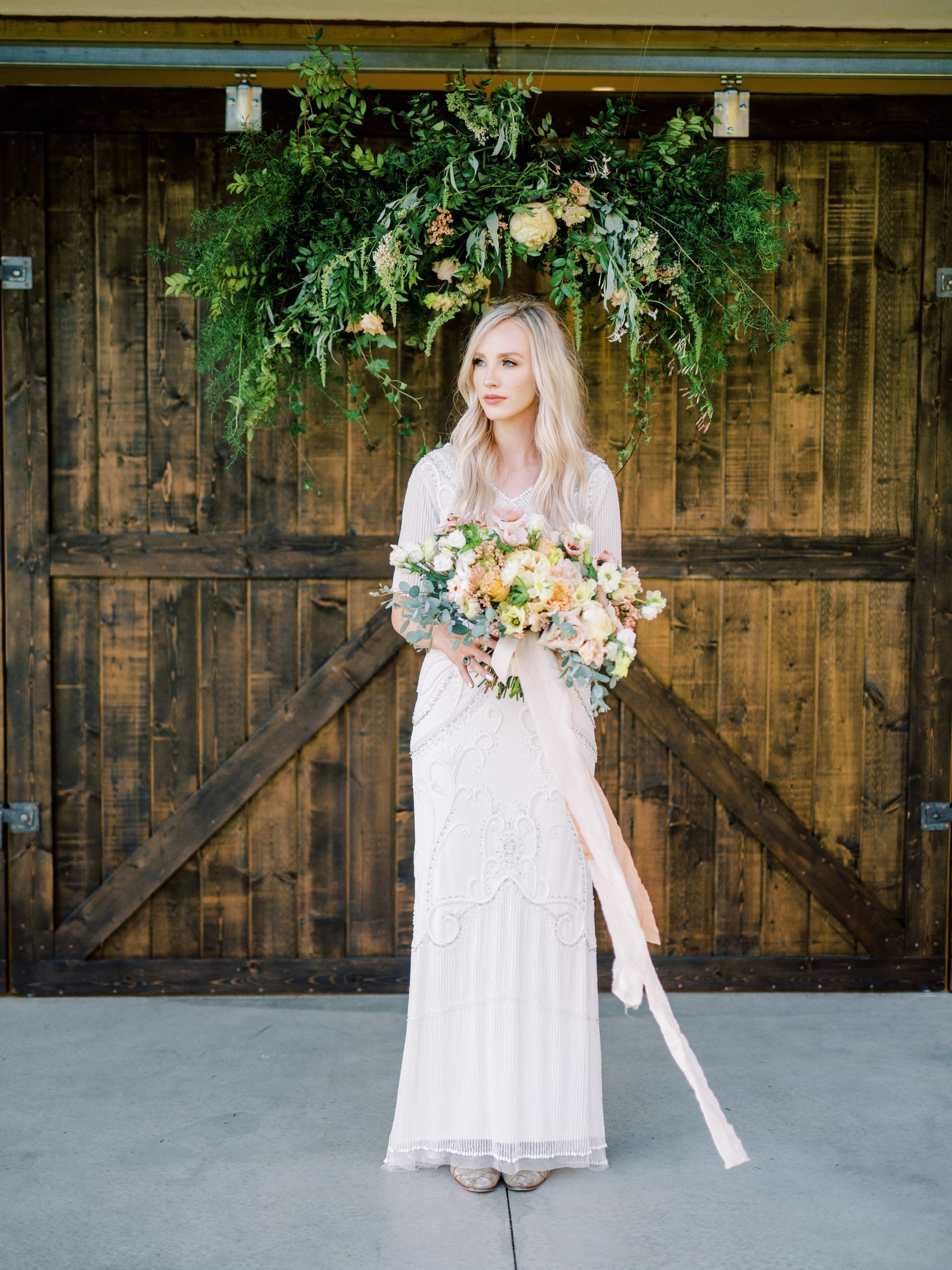 A bride in a white dress is holding a bouquet of pink and white flowers.