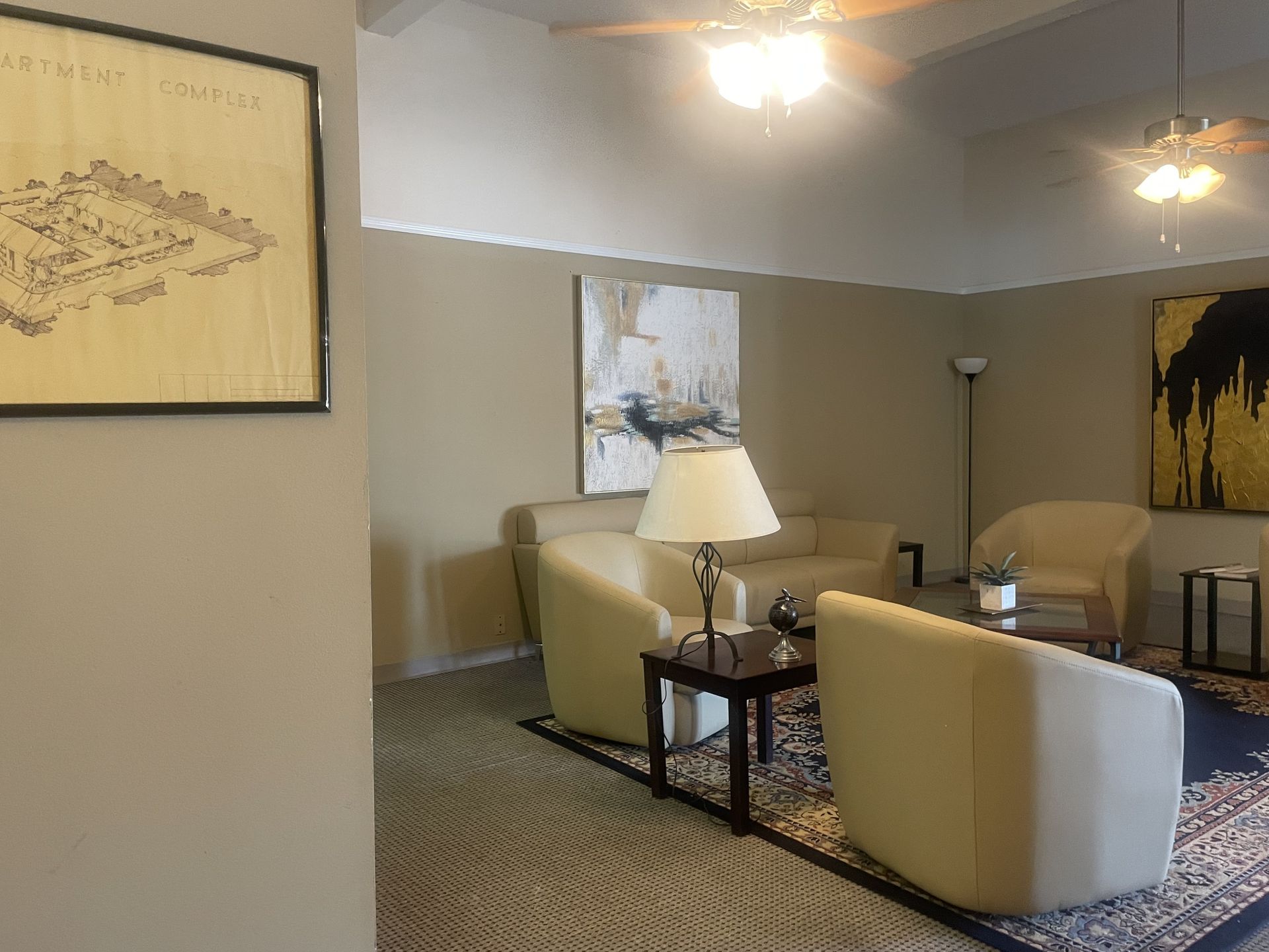 Living room with neutral walls, cream-colored furniture, rug, and artwork.