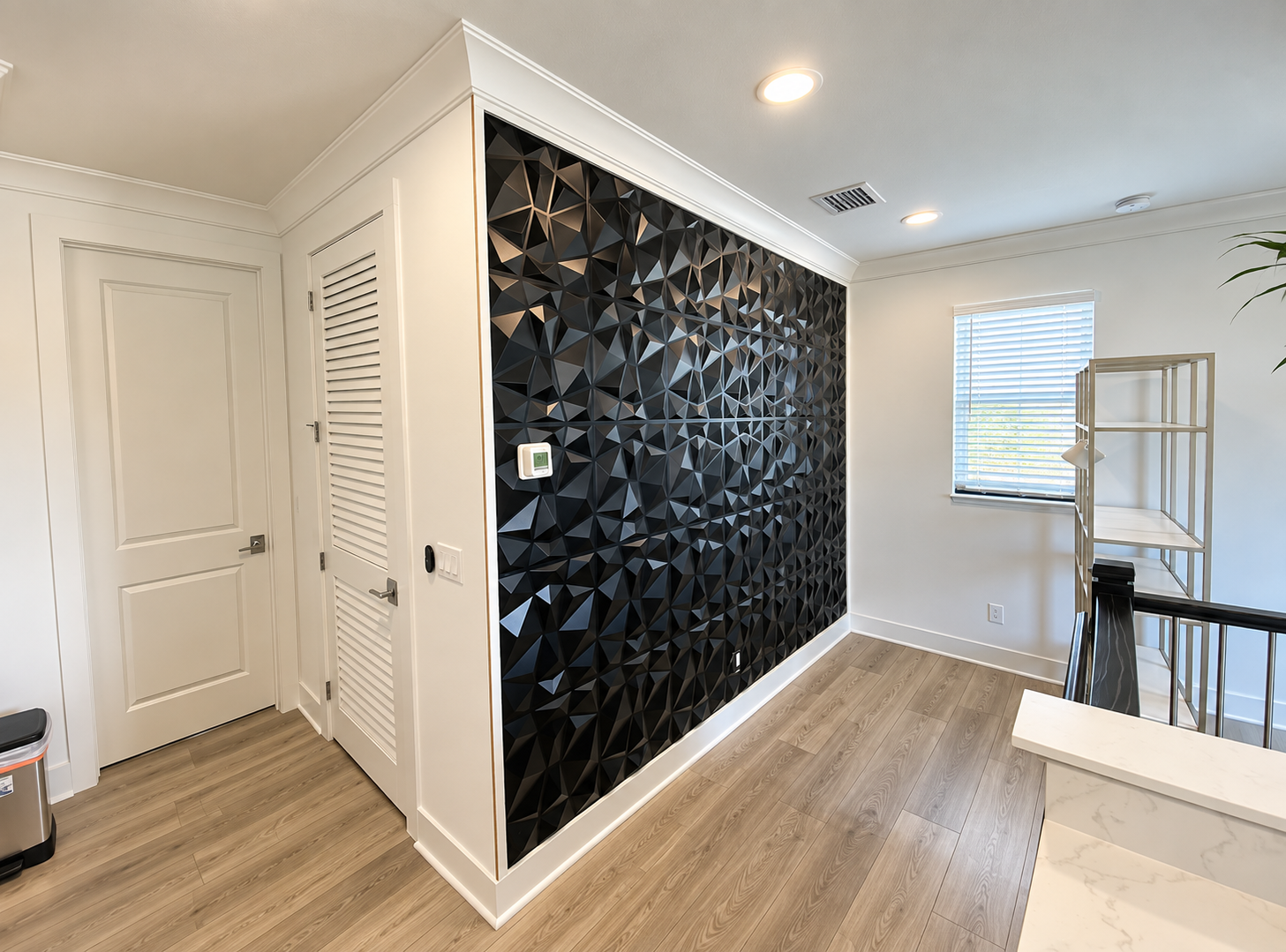 Modern entry hall with black geometric accent wall, white trim, and light wood flooring