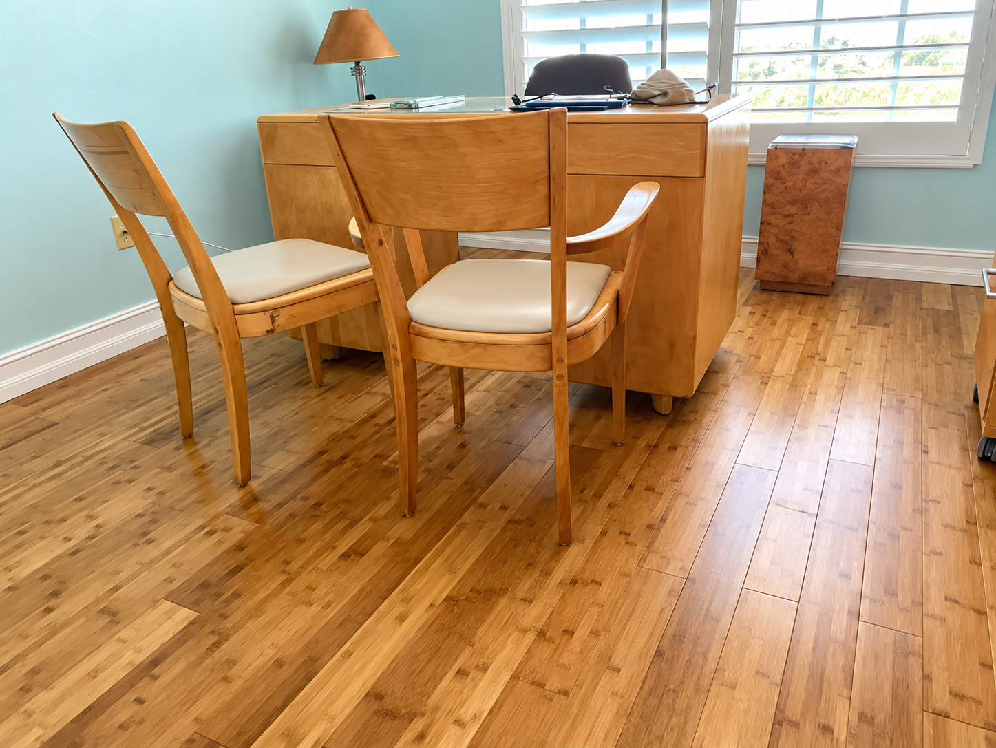 Wooden dining table and chairs in a bright room with bamboo flooring and a window.