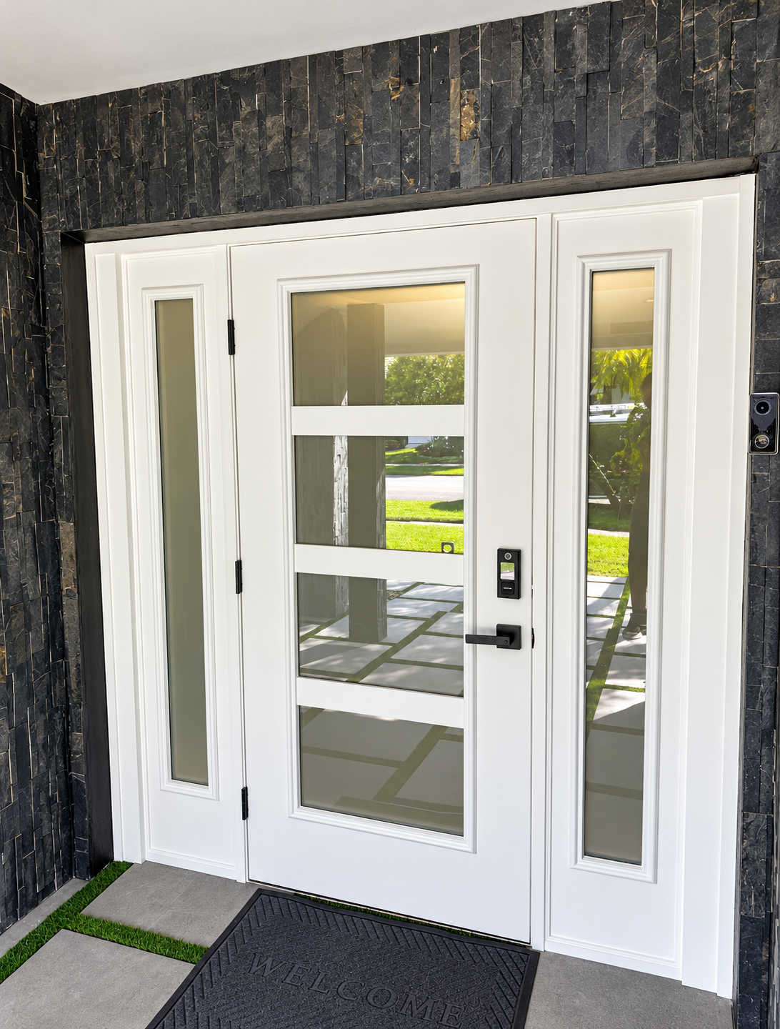 White front entry door with sidelights and glass panels set in a dark stone exterior.