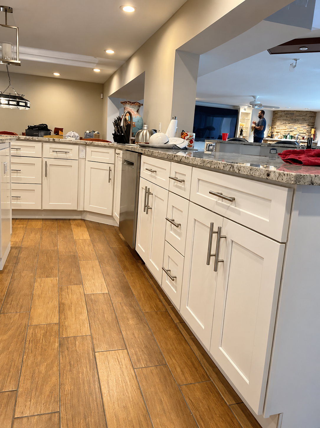 Modern kitchen with white cabinets, granite counters, wood floor, and recessed ceiling lights