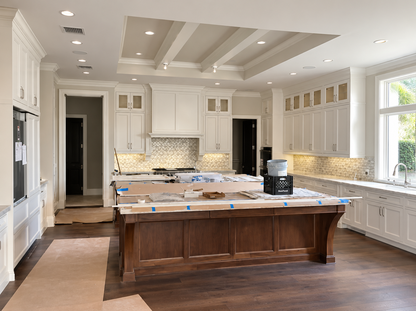 Bright white kitchen with a large wooden island, marble countertops, and recessed ceiling lights