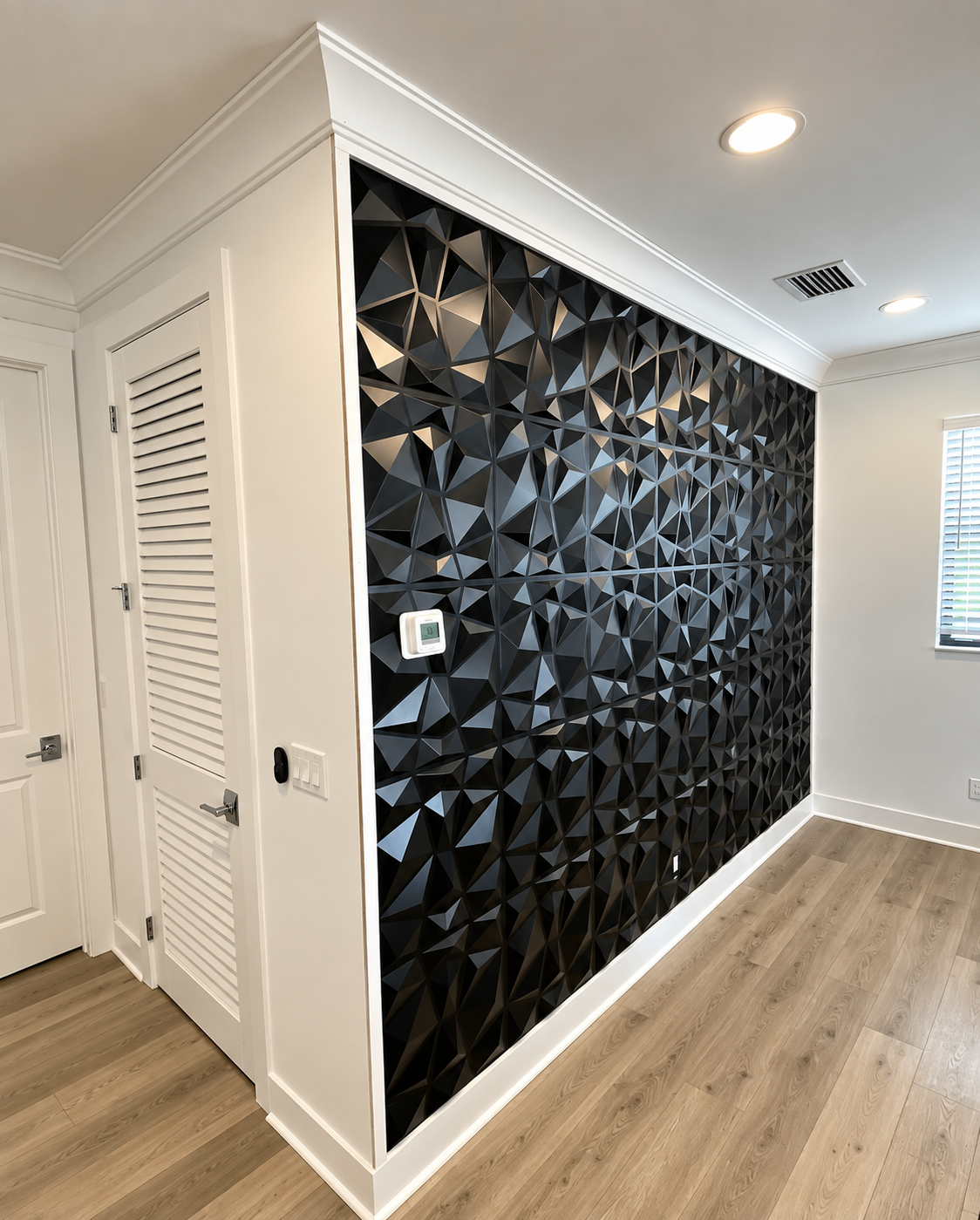 Modern hallway with a black geometric accent wall, white trim, and light wood flooring