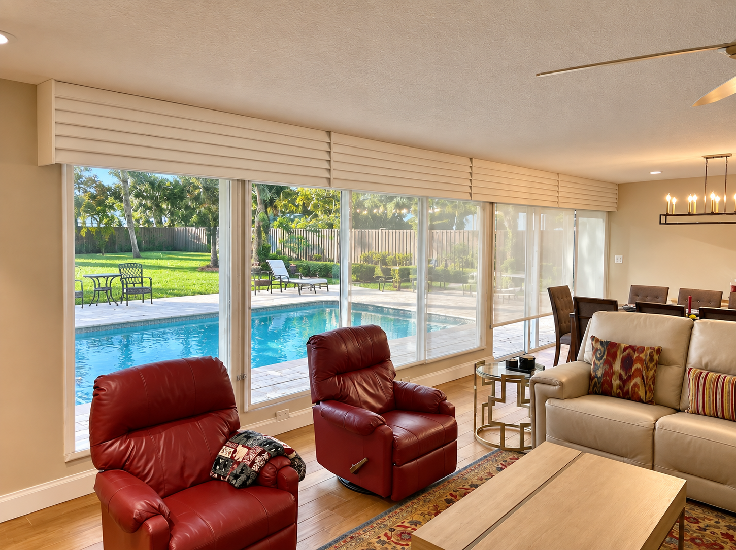 Living room with red chairs overlooking a backyard pool through large windows