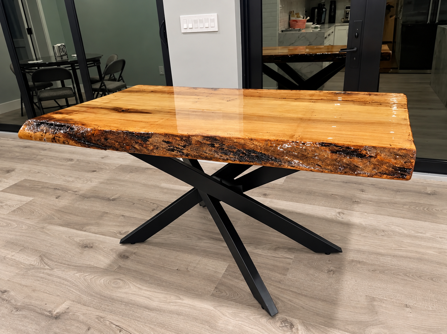 Live-edge wooden table with black X-shaped metal legs in an indoor showroom