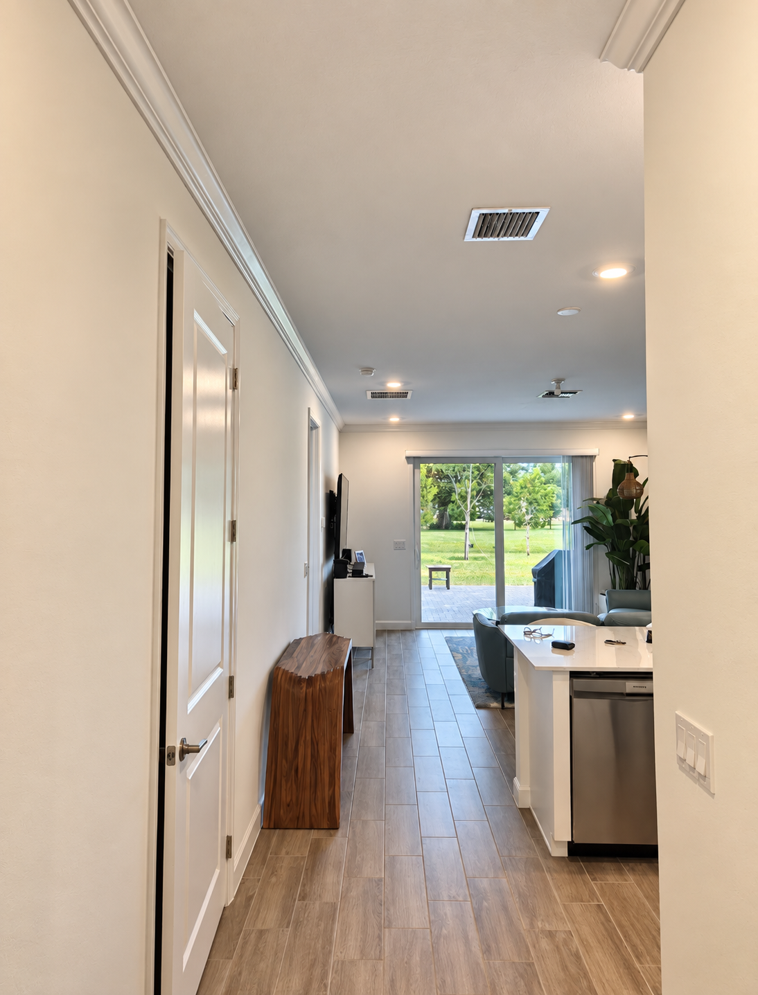 Bright open hallway leading to a modern kitchen with wood floors and a view of the backyard.