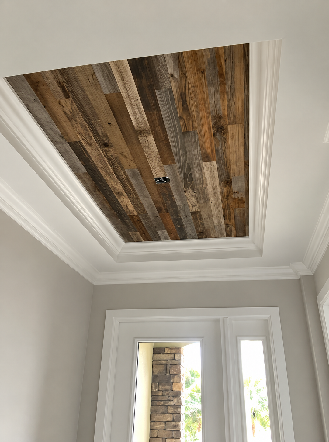 Ceiling with exposed rustic wood planks in a white room above a doorway