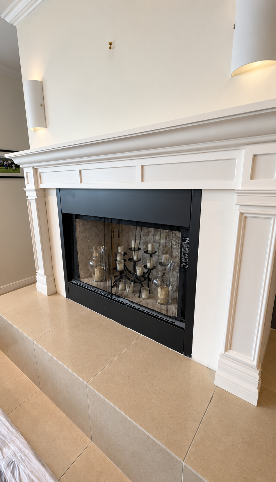 White fireplace with black glass insert and white mantel in a bright room with beige tile floor