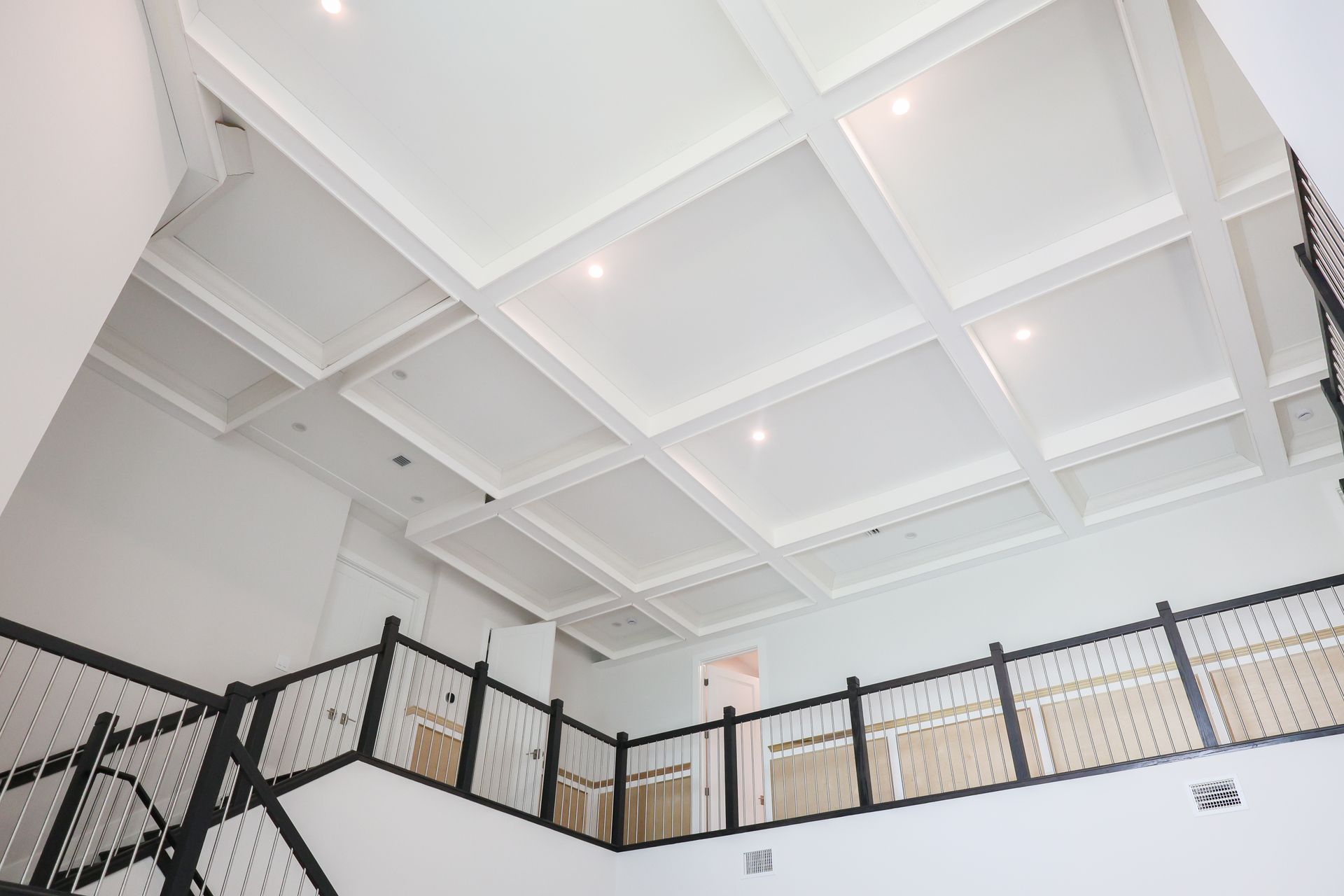 White interior atrium ceiling with recessed lights and black metal railings below