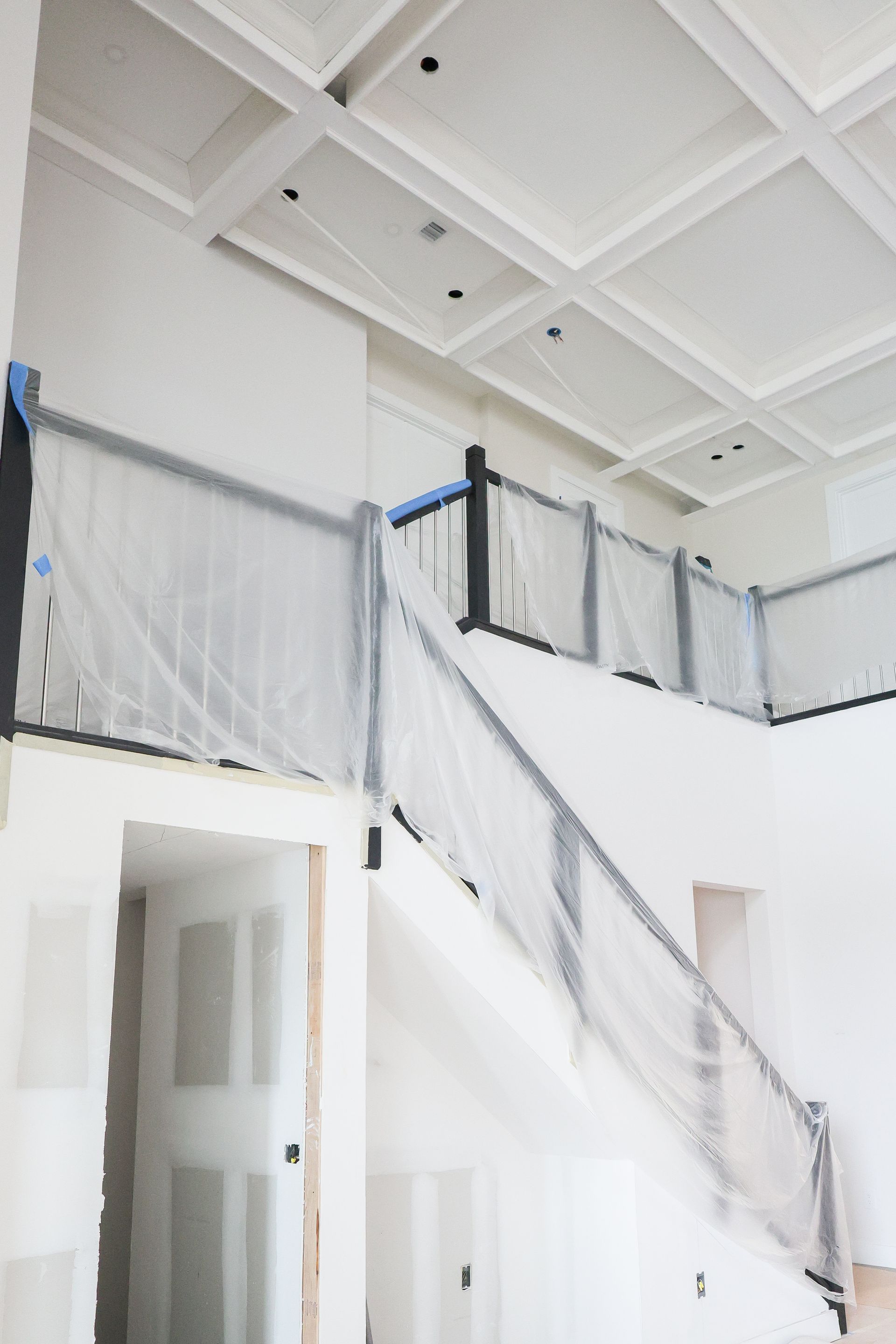 Bright white interior with staircase, glass railing, and open second-floor landing.