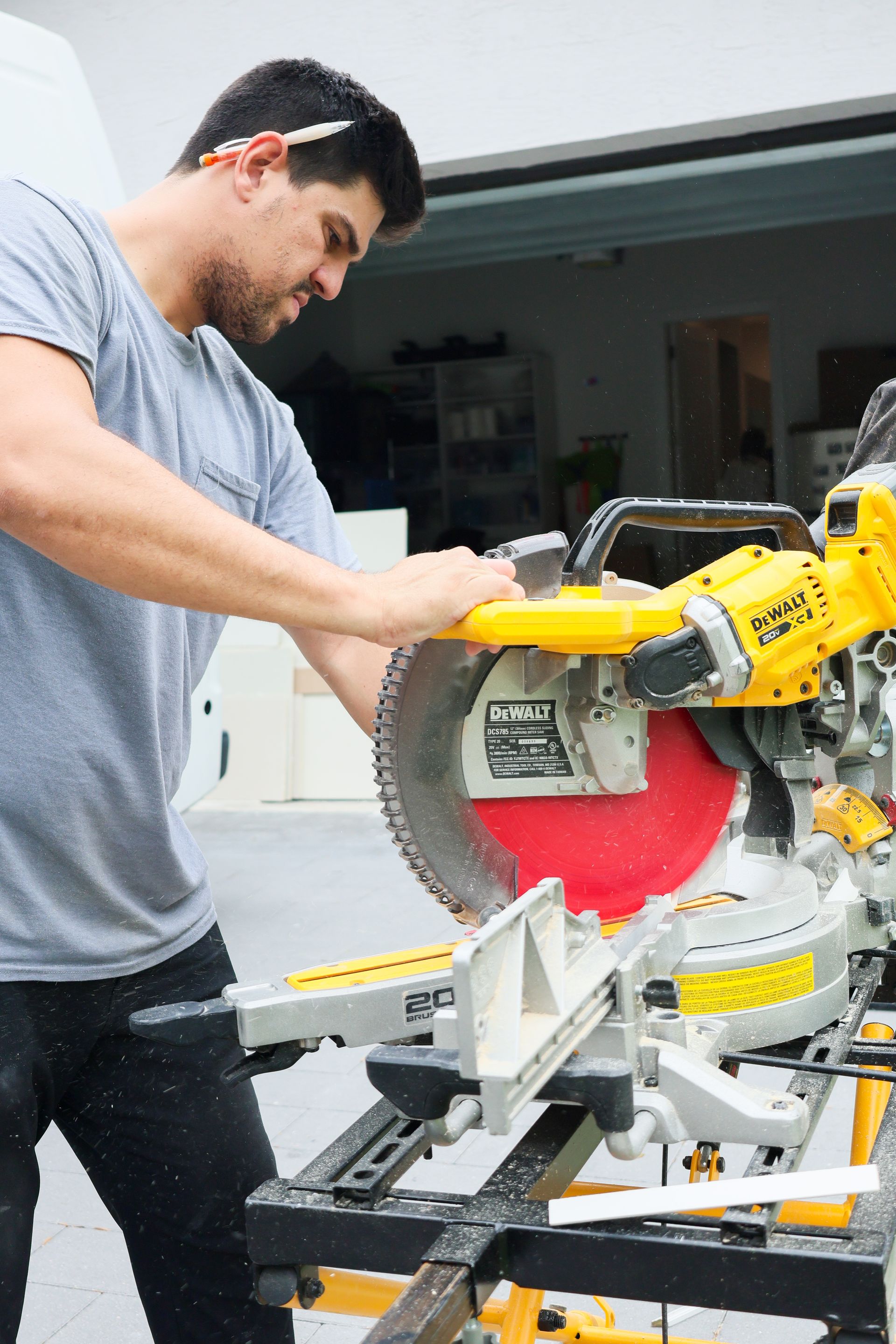 Man using a yellow miter saw to cut wood in a garage