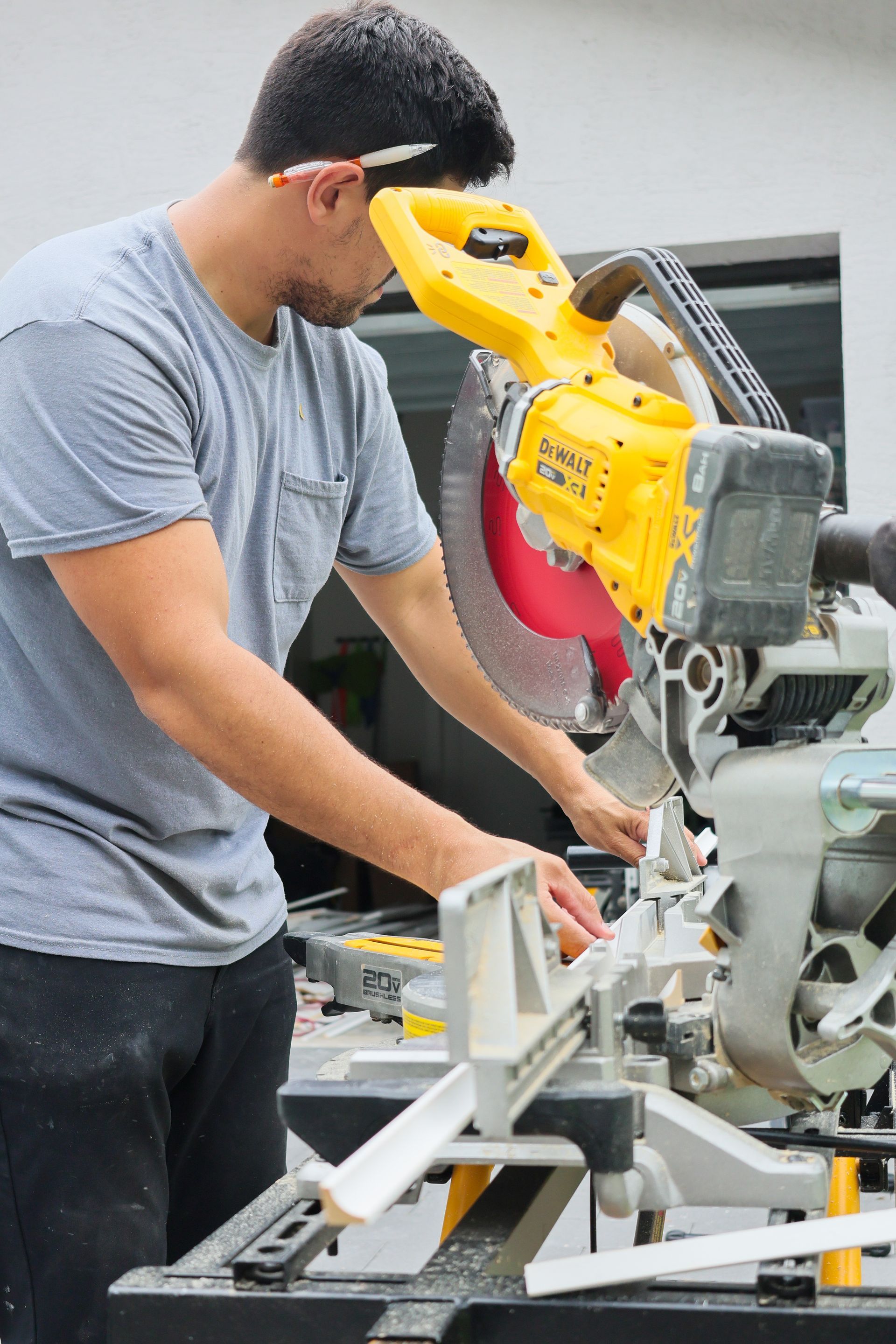 Person using a yellow miter saw in a workshop, cutting a piece of wood.